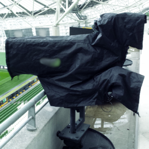 Black fabric camera cover on a camera outside on a balcony.