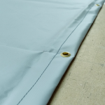 A grey PVC groundsheet with brass eyelets in a stitched hem.